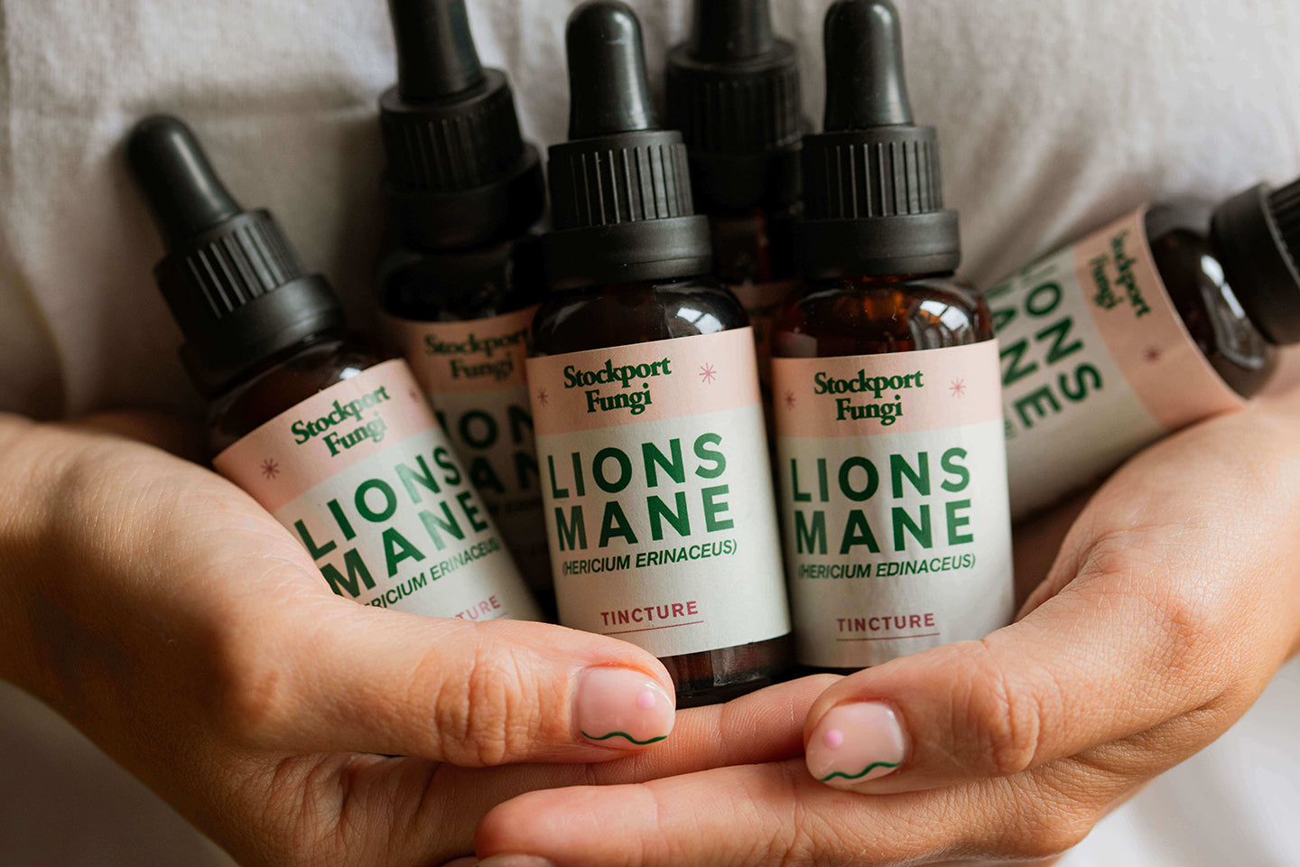 multiple bottles of lions mane mushroom tincture being held in some hands
